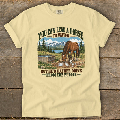 A light yellow t-shirt with a vintage graphic of a horse drinking from a puddle.