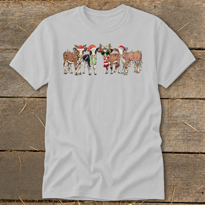 Five cartoon cows wearing Santa hats and festive lights.