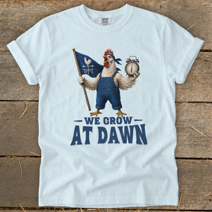 Chicken wearing overalls holding flag and alarm clock with text "WE GROW AT DAWN".