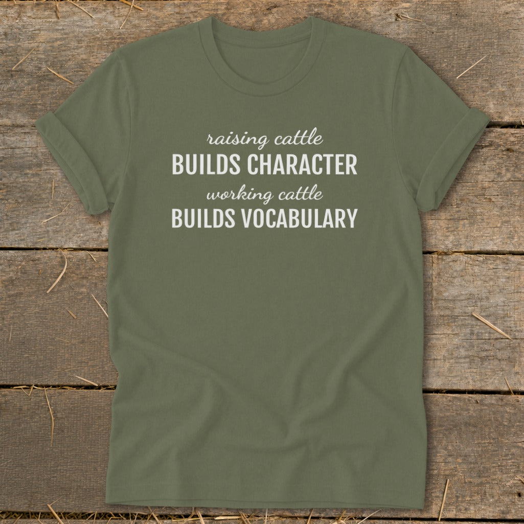 Green t-shirt with text "raising cattle BUILDS CHARACTER working cattle BUILDS VOCABULARY".