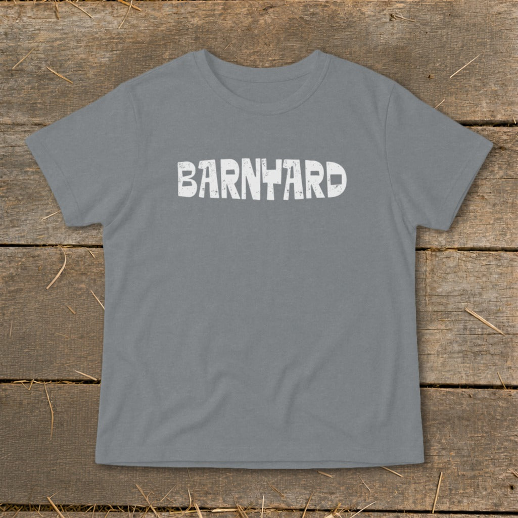 A gray crewneck t-shirt with distressed white text reading BARNYARD centered on the chest, laid flat on a rustic wooden background.