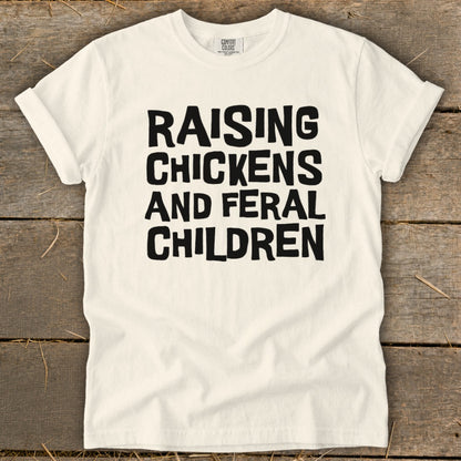 White t-shirt with black text: "Raising Chickens and Feral Children"