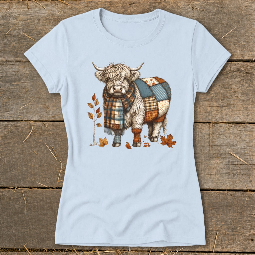 Highland cow with a patchwork coat and plaid scarf, surrounded by autumn leaves.