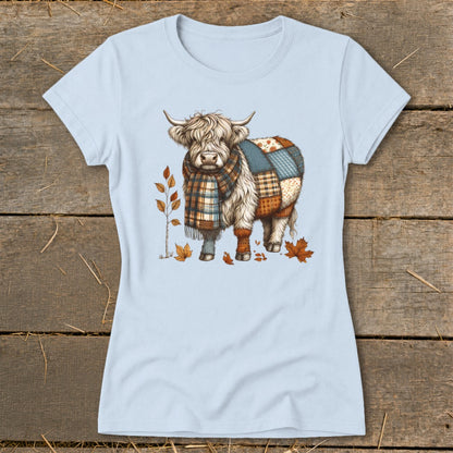 Highland cow with a patchwork coat and plaid scarf, surrounded by autumn leaves.