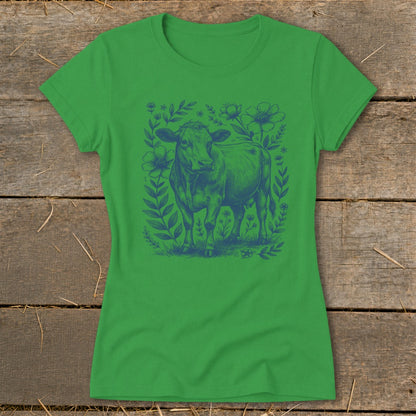 Green t-shirt with a blue line drawing of a cow surrounded by flowers and leaves.