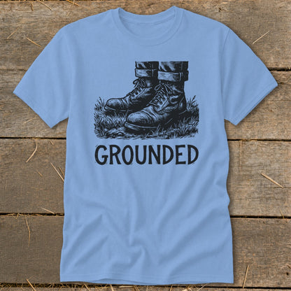 Light blue t-shirt with a graphic of boots in grass and the word "GROUNDED".