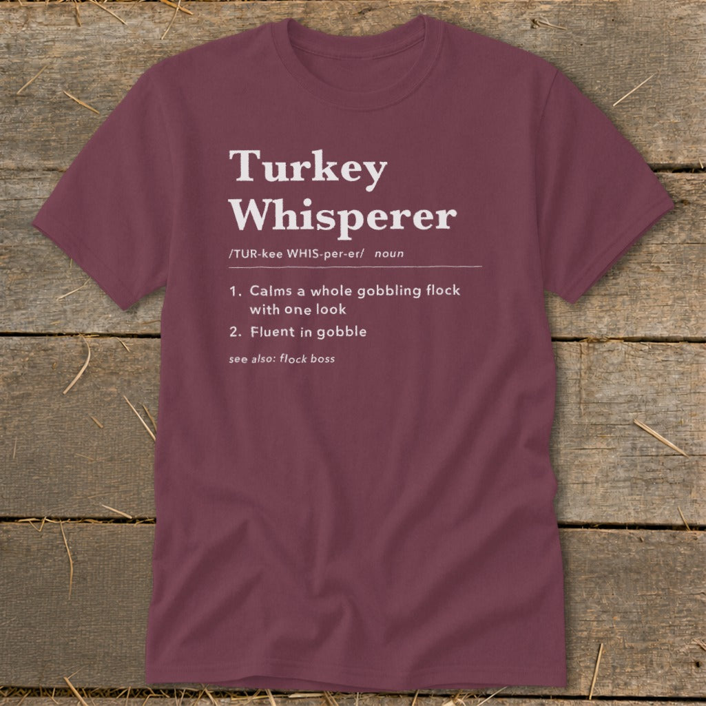 Maroon t-shirt with "Turkey Whisperer" definition: calms flock, fluent in gobble.