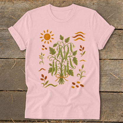 Pink t-shirt with a botanical print of pea pods, sun, and leaves.