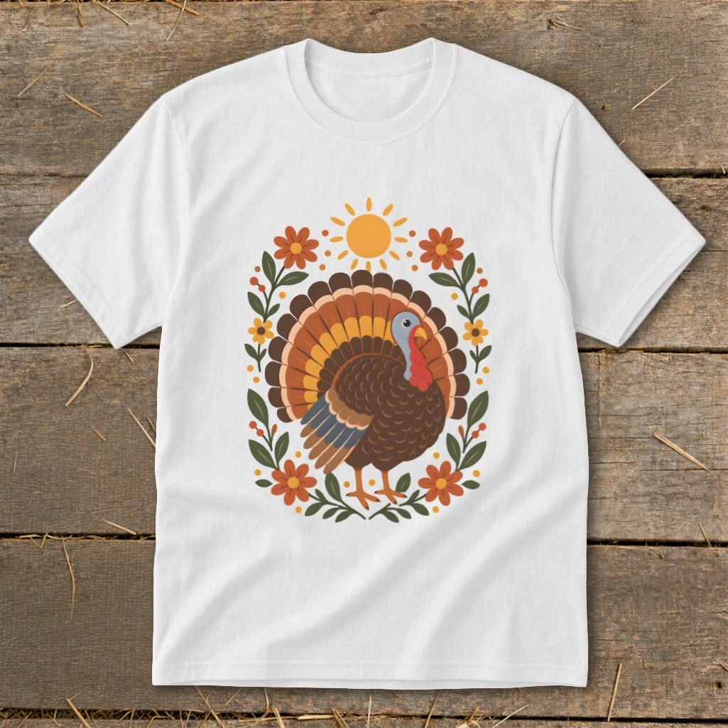 White t-shirt with a stylized turkey and floral design on a wooden background.