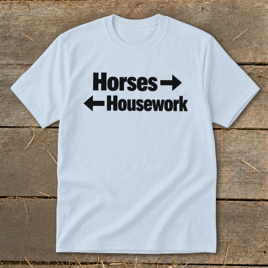 Light blue crew neck t-shirt with black text that reads Horses with a right-pointing arrow above Housework with a left-pointing arrow.