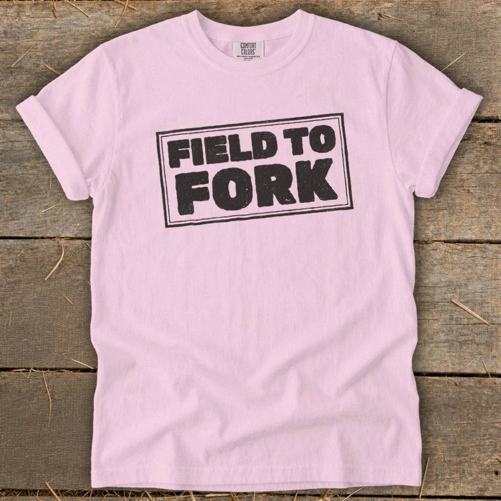 Light pink t-shirt with rolled sleeves featuring a black distressed box design with the text "FIELD TO FORK".