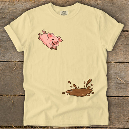 Yellow t-shirt with a cartoon pig jumping over a puddle of mud.