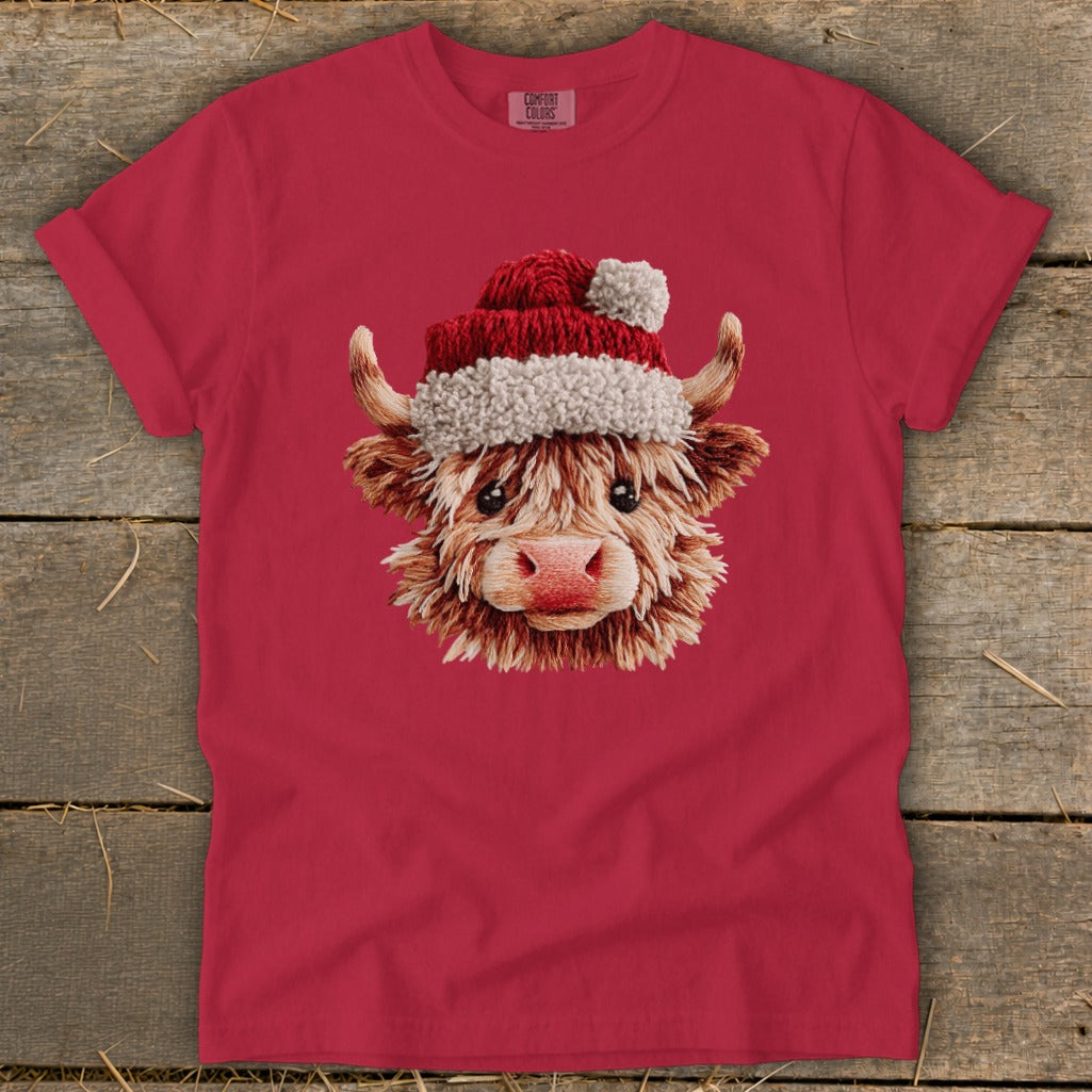 Highland cow wearing a Santa hat on a red t-shirt.