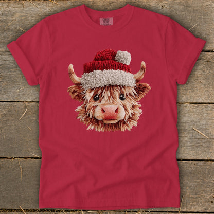 Highland cow wearing a Santa hat on a red t-shirt.