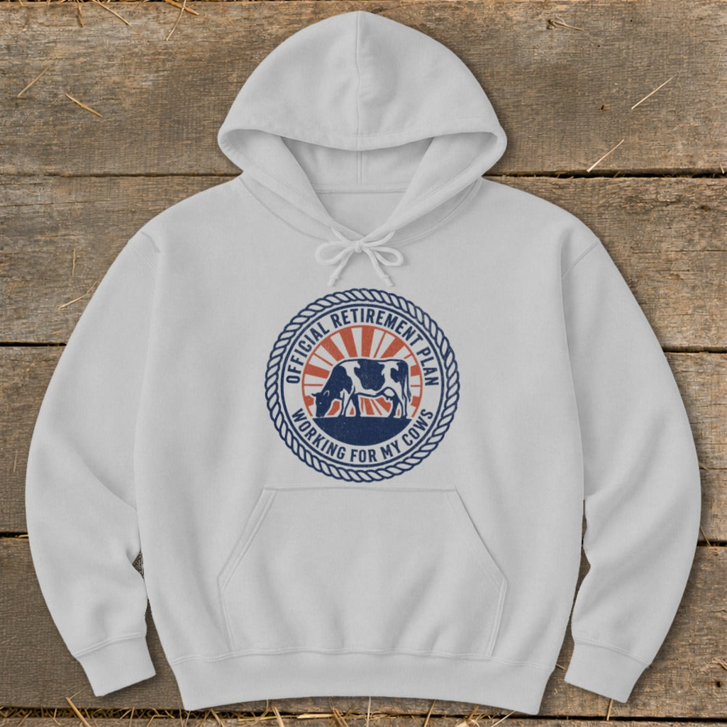 White hoodie with a circular graphic featuring a cow and text "Official Retirement Plan Working For My Cows".