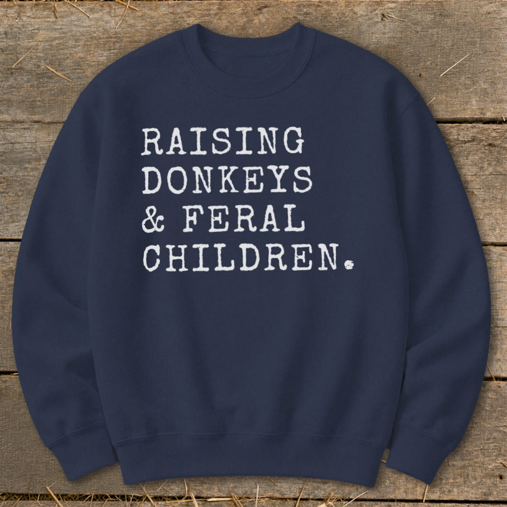 Navy sweatshirt with white text that reads "Raising Donkeys & Feral Children."