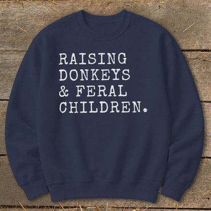 Navy sweatshirt with white text that reads "Raising Donkeys & Feral Children."