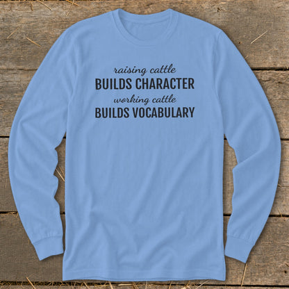 Light blue long-sleeve shirt with text "raising cattle BUILDS CHARACTER working cattle BUILDS VOCABULARY".