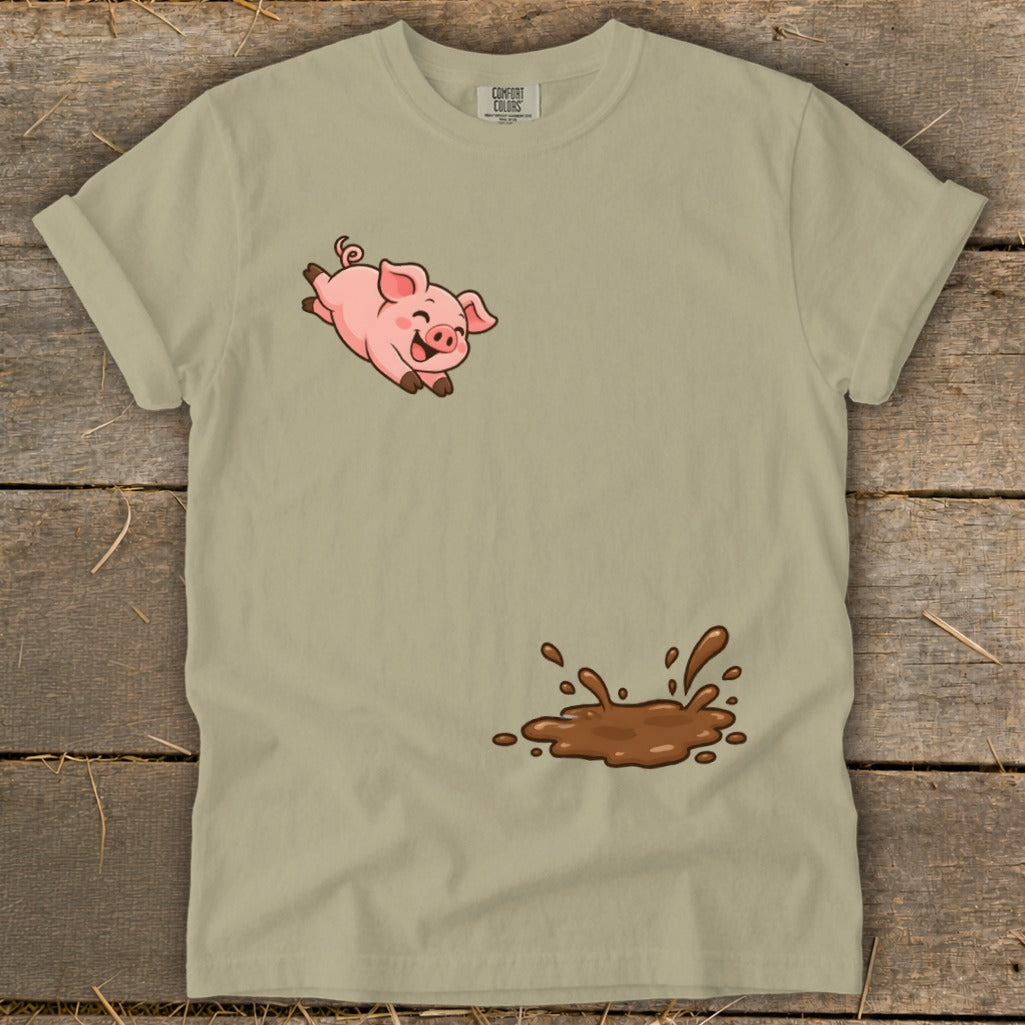 Tan t-shirt with cartoon pig jumping over a mud puddle graphic.