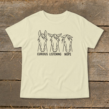 Light yellow t-shirt featuring a black graphic of three horse heads with the text "CURIOUS LISTENING NOPE".