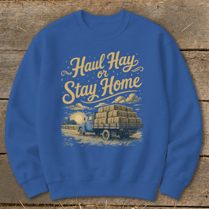 Blue sweatshirt with "Haul Hay or Stay Home" text and illustration of a truck loaded with hay bales.