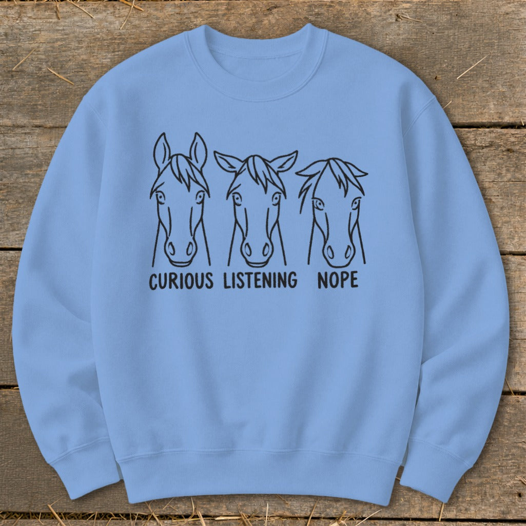 Light blue crewneck sweatshirt featuring three horse head sketches with the captions curious, listening, and nope.