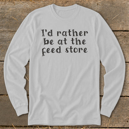 White long-sleeve shirt with black text reading "I'd rather be at the feed store."