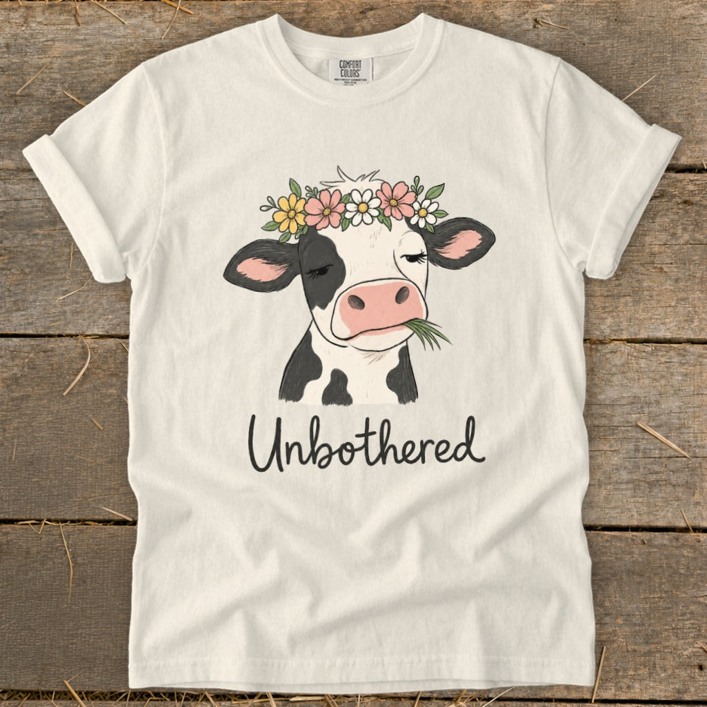 T-shirt with cartoon cow wearing flower crown, eating grass, and text "Unbothered".