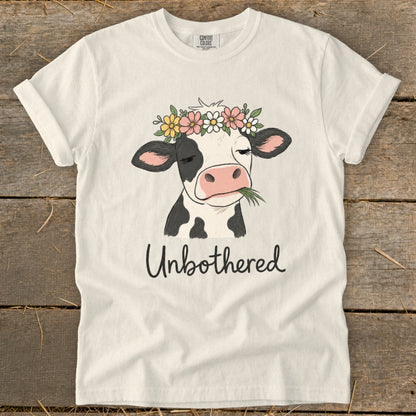 T-shirt with cartoon cow wearing flower crown, eating grass, and text "Unbothered".