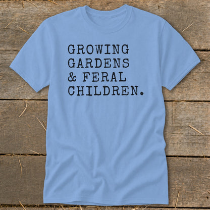 Light blue t-shirt with black text reading "GROWING GARDENS & FERAL CHILDREN."