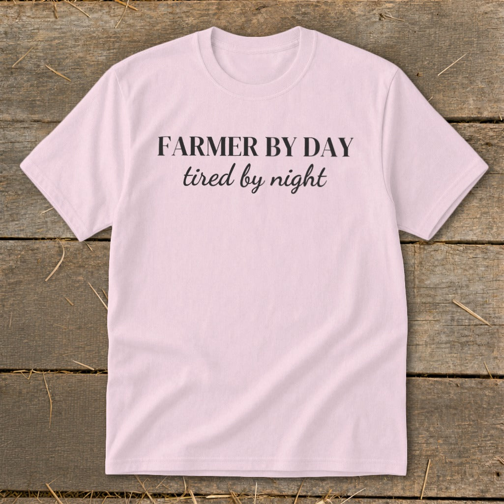 Pink t-shirt with black text that reads "FARMER BY DAY tired by night".