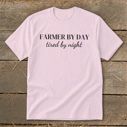 Pink t-shirt with black text that reads "FARMER BY DAY tired by night".