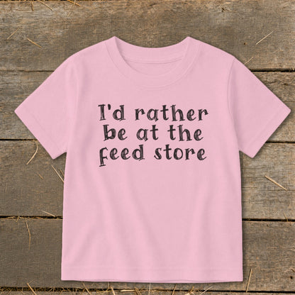 Pink t-shirt with black text that reads "I'd rather be at the feed store."
