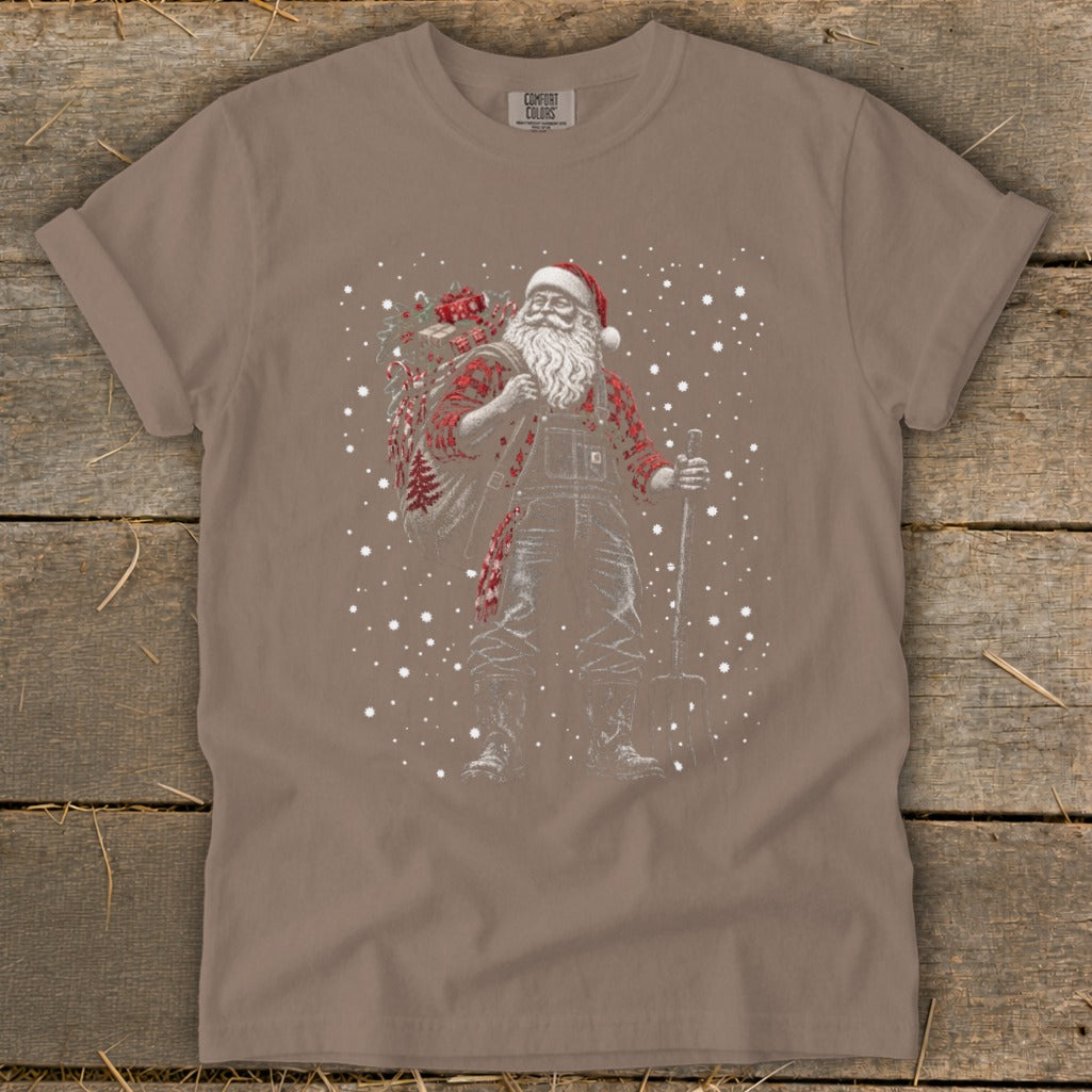 Santa Claus wearing overalls and flannel, carrying a sack and shovel, with falling snow.