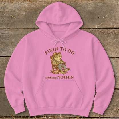Pink hoodie with frog sitting in rocking chair, text "FIXIN TO DO absolutely NOTHIN".