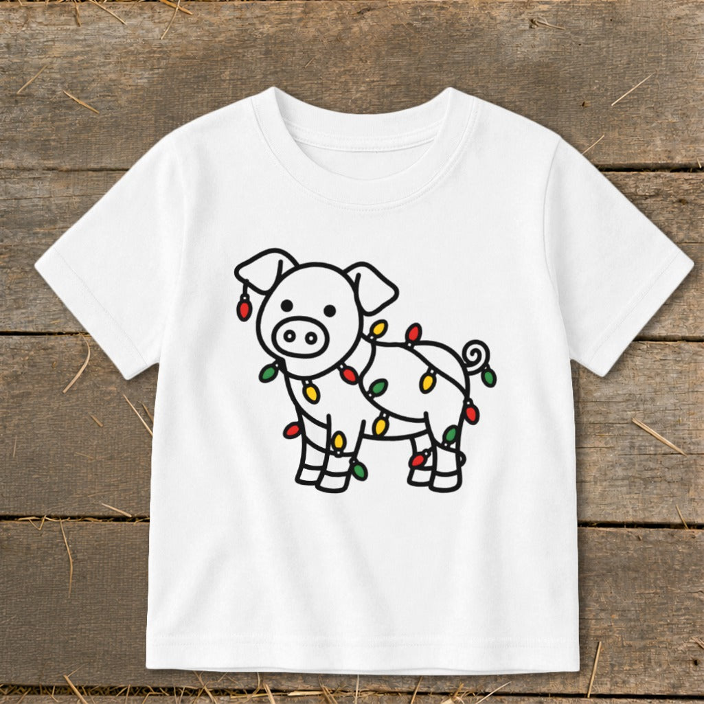 A white short-sleeve children's t-shirt featuring a black-outline graphic of a pig tangled in colorful Christmas lights.