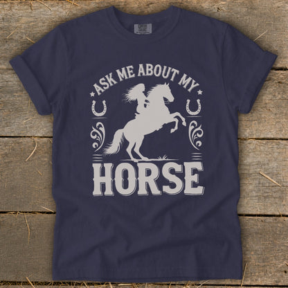 Navy t-shirt with silver graphic of a woman riding a bucking horse and text "Ask Me About My Horse".