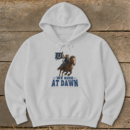 White hoodie with graphic of cat riding horse, holding a blue flag, and text "WE RIDE AT DAWN".