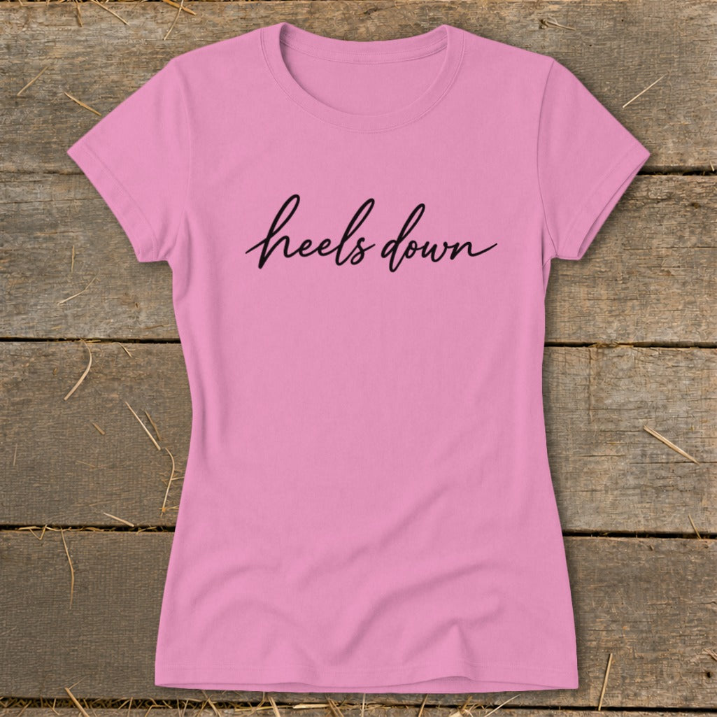 Pink t-shirt with "heels down" text in black cursive script.