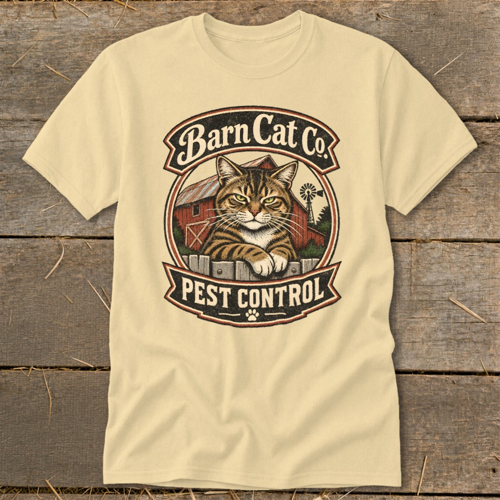 A light yellow t-shirt features a vintage graphic of a tabby cat behind a fence with a red barn and windmill in the background, text that reads Barn Cat Co. and PEST CONTROL.