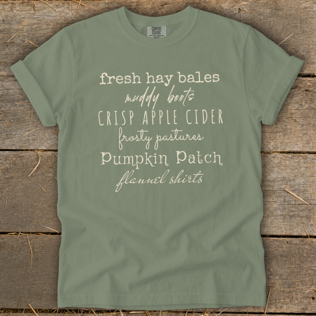 Sage green t-shirt with white text listing fall phrases.