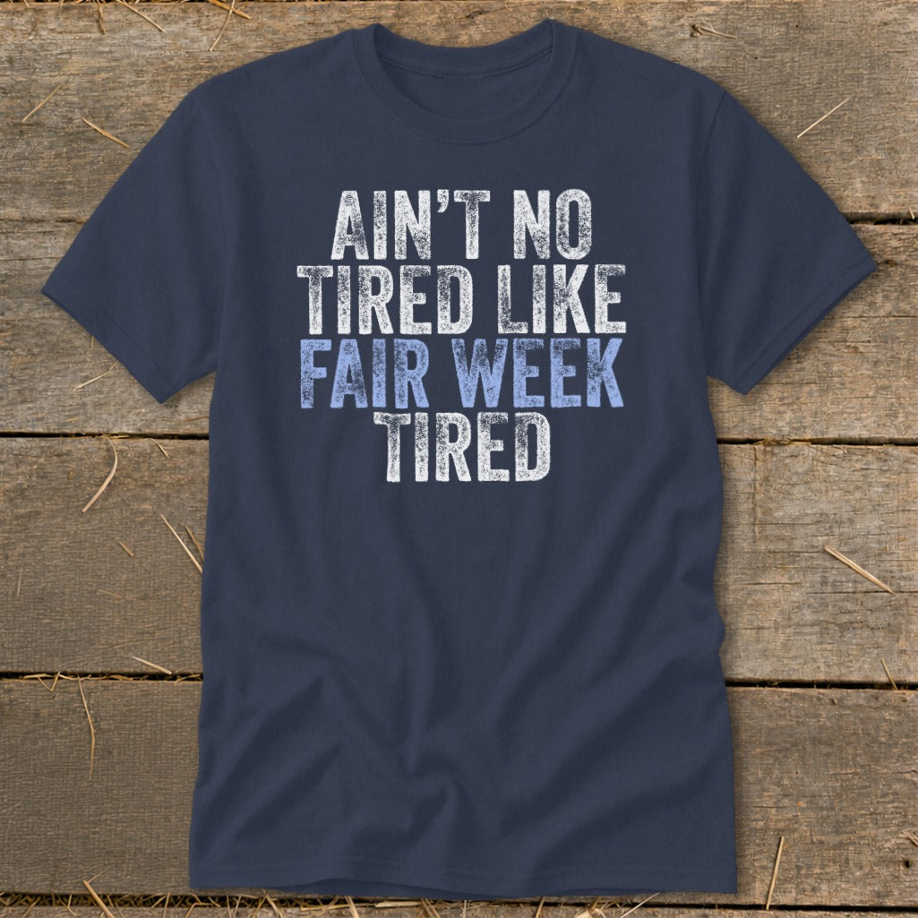 Navy t-shirt with white and blue text reading "Ain't no tired like fair week tired."