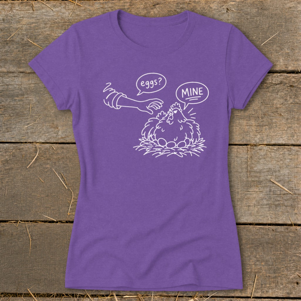 Purple t-shirt with graphic of a hen protecting eggs from a hand labeled "eggs?".