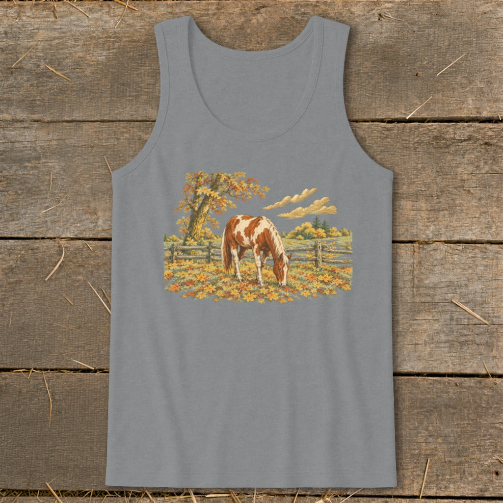 Pinto horse grazing in a field of autumn leaves with a wooden fence.