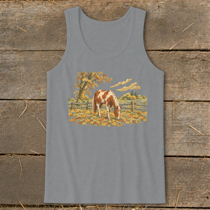 Pinto horse grazing in a field of autumn leaves with a wooden fence.