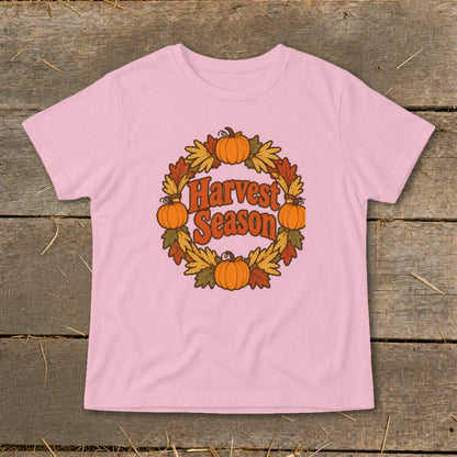 Pink t-shirt with a floral wreath of pumpkins and leaves, featuring "Harvest Season" text.