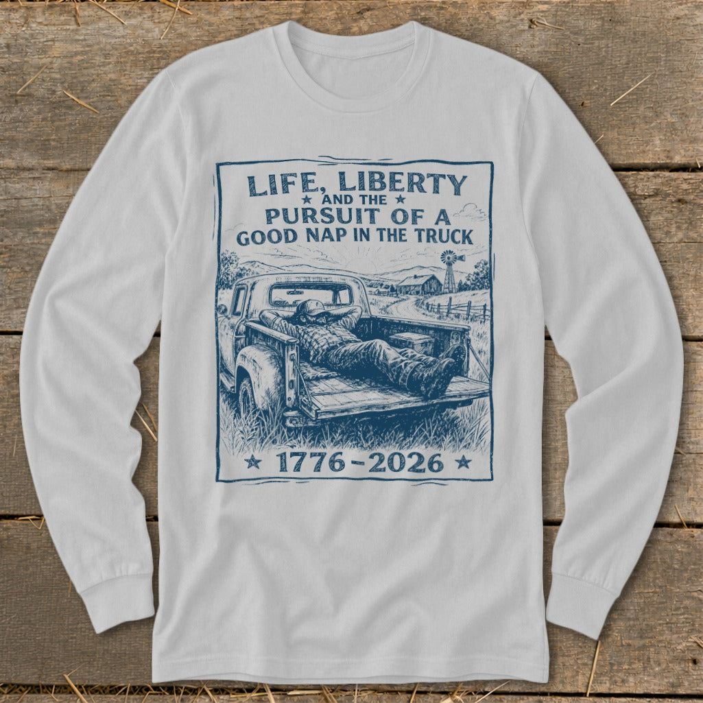 White long-sleeve shirt with graphic: "Life, Liberty, Pursuit of a Good Nap in the Truck" and "1776-2026".