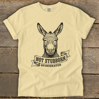 Light yellow t-shirt with black ink drawing of a donkey head and text "NOT STUBBORN OPINIONATED".