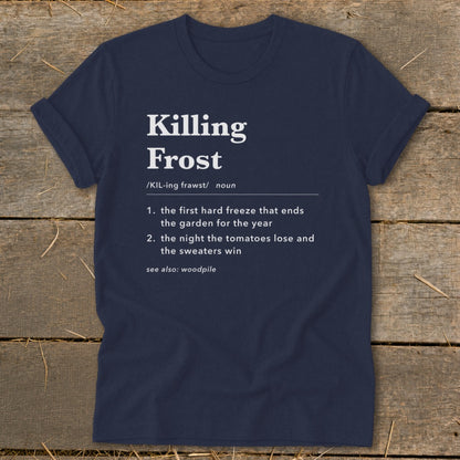 Navy blue t-shirt featuring dictionary definition text for Killing Frost centered on the chest, laid flat on a rustic wooden surface.