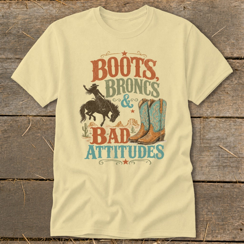 T-shirt graphic with text "Boots, Broncs & Bad Attitudes," cowboy, and boots.